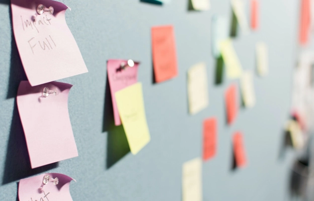 Pin board with used memo stick papers in different colors in order to carry out web development project with agile methodology